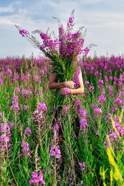 Junge Frau, die den Blumenstrauß der rosa Blumen hält.