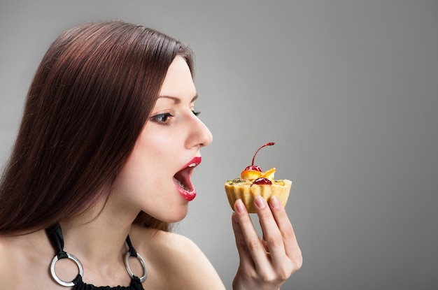 Foto junge frau, die den kuchen in ihren händen betrachtet