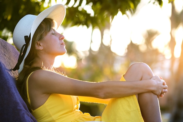 Junge Frau, die draußen an sonnigem Sommertag entspannt