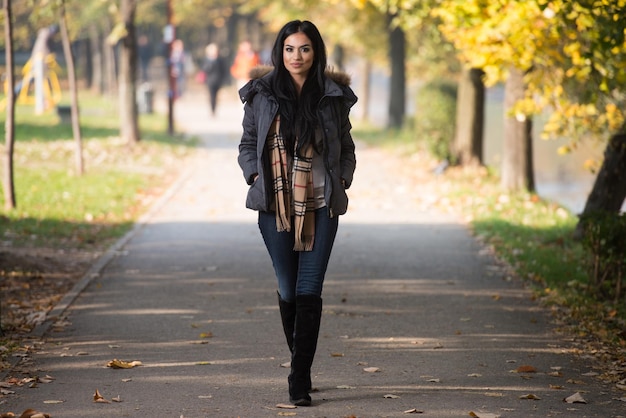 Junge Frau, die draußen im Herbst im Wald durch den Wald spaziert