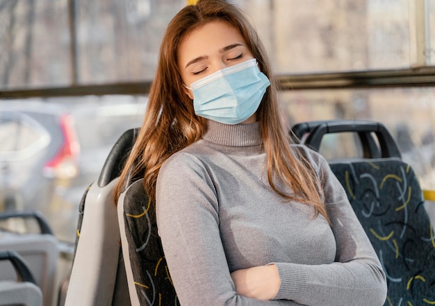 Foto junge frau, die durch stadtbus mit chirurgischer maske reist