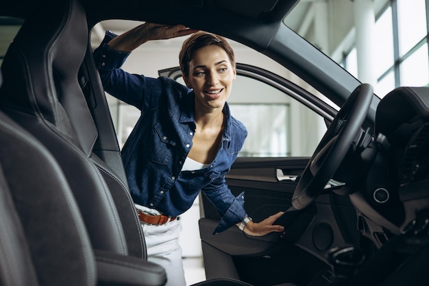 Junge Frau, die ein Auto im Autohaus auswählt