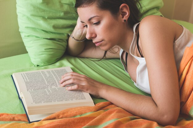 Junge Frau, die ein Buch auf dem Bett liest