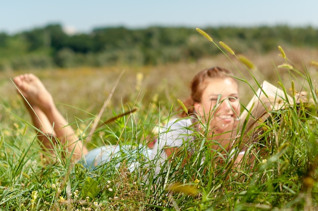 junge Frau, die ein Buch liest, das auf dem Gras liegt