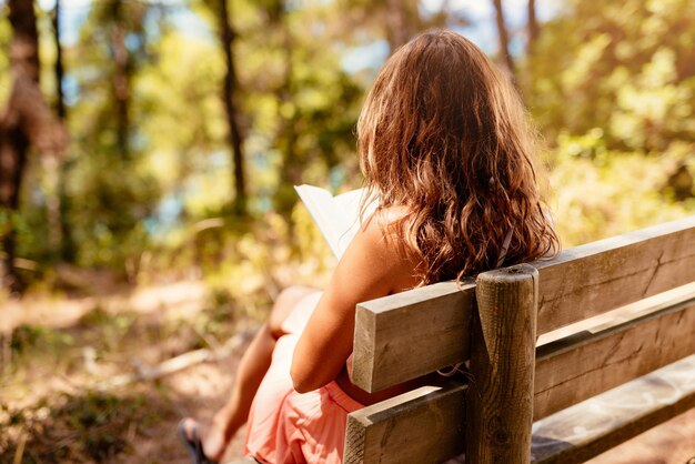 Junge Frau, die ein Buch liest, während sie sich im Wald entspannt.