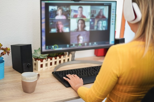 Junge Frau, die ein Diskussionstreffen im Videoanruf mit ihrem Team hat - Fokus auf der linken Hand