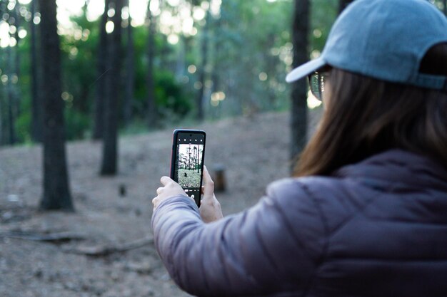 Foto junge frau, die ein foto im wald macht