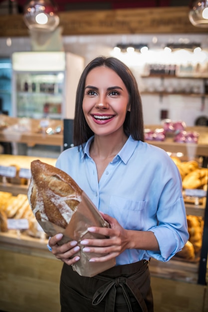 Junge Frau, die ein frisch gebackenes Brot hält