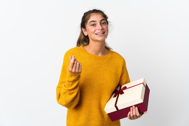 Junge Frau, die ein Geschenk lokalisiert auf Weiß macht, das Geldgeste macht