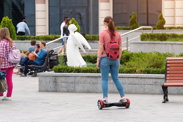 Junge Frau, die ein Hoverboard auf dem Stadtplatz reitet