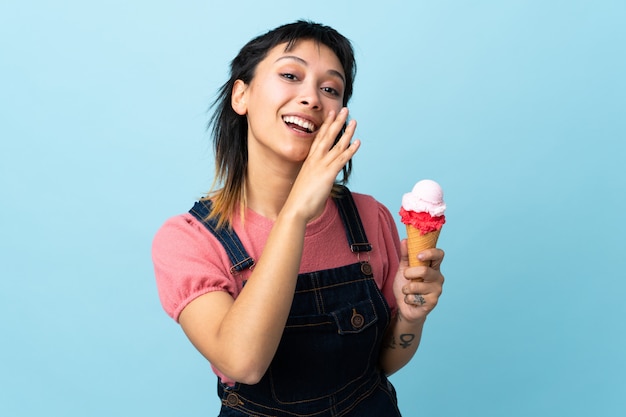 Junge Frau, die ein Kornett-Eis über dem isolierten blauen Raum hält, der etwas flüstert