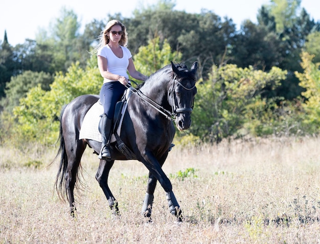 Junge Frau, die ein Pferd in der Natur reitet