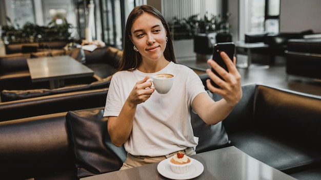 Foto junge frau, die ein selfie am kaffeehaus nimmt