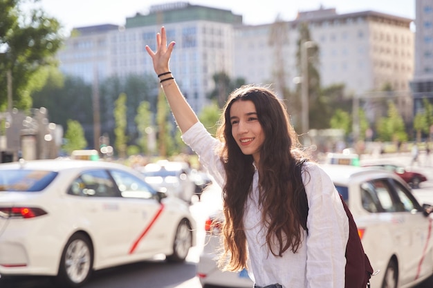 Junge Frau, die ein Taxi auf der Straße der Stadt anhält Konzept von Transport, Reisen und Tourismus