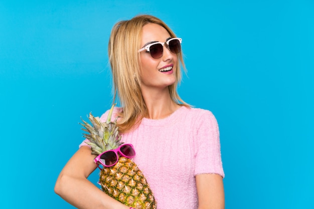 Junge Frau, die eine Ananas mit Sonnenbrille hält