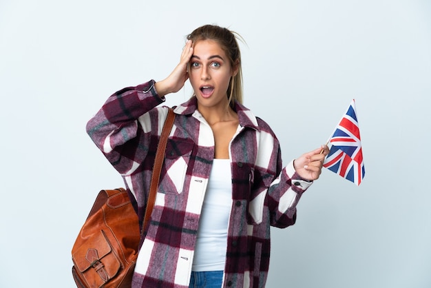 Junge Frau, die eine britische Flagge auf Weiß mit Überraschungsausdruck hält