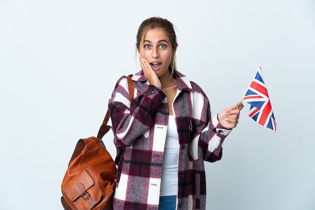 Junge Frau, die eine britische Flagge hält, die lokal gegen die leere Wand aufwirft