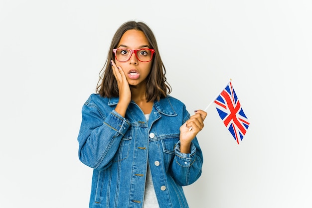 Junge Frau, die eine englische Flagge lokalisiert auf weißer Wand hält, beeindruckte das Halten des Kopienraums auf Palme