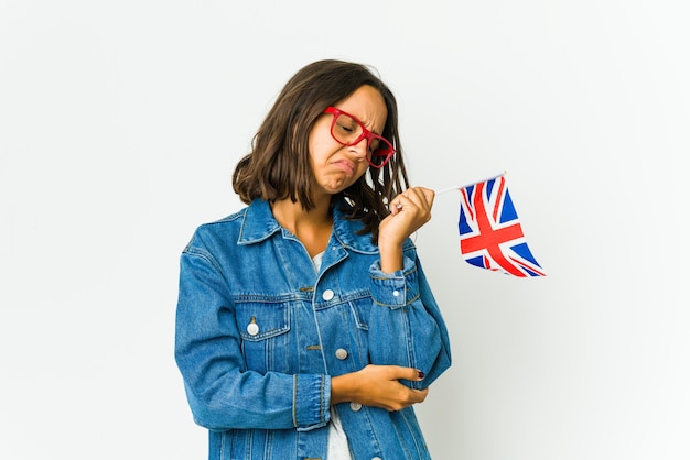 Junge frau, die eine englische flagge lokalisiert auf weißer wand hält, die ellbogen massiert und nach einer schlechten bewegung leidet