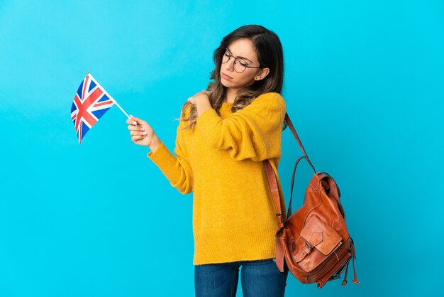 Junge Frau, die eine Flagge des Vereinigten Königreichs hält, die lokal gegen die leere Wand aufwirft