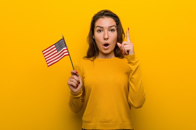 Junge Frau, die eine Flagge Vereinigter Staaten hat irgendeine großartige Idee, Konzept der Kreativität hält.