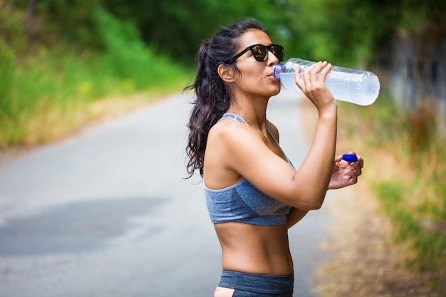 junge Frau, die eine Flasche im Wald hält