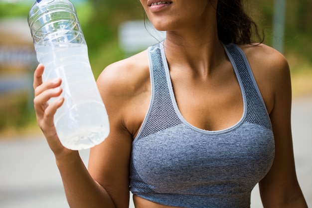 junge Frau, die eine Flasche im Wald hält