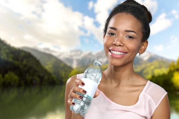 Junge Frau, die eine Flasche Wasser zeigt