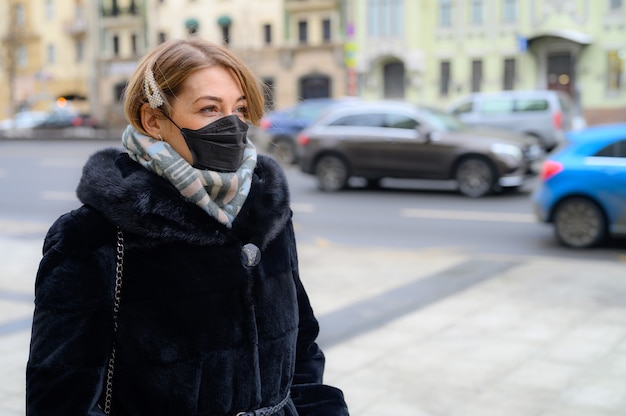 Junge Frau, die eine Gesichtsmaske im Freien trägt