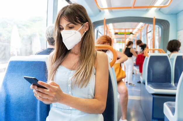 Junge Frau, die eine Gesichtsmaske trägt, die öffentliche Verkehrsmittel reitet.