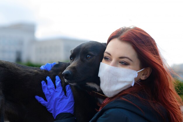 Junge Frau, die eine Gesichtsmaske verwendet, die mit ihrem Hund geht.