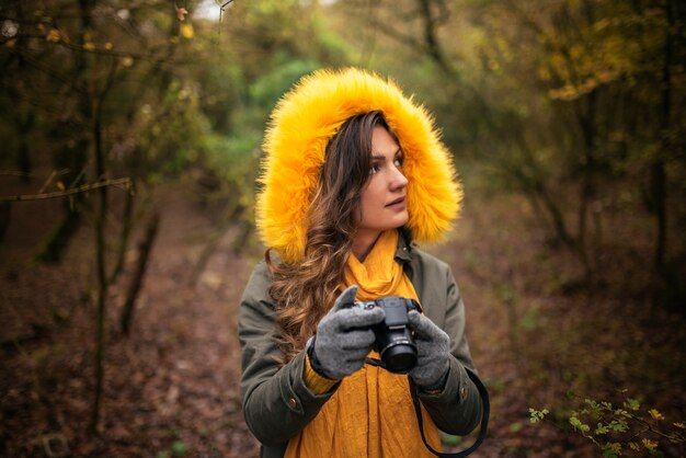 Junge Frau, die eine Kamera verwendet, um im Wald zu fotografieren.
