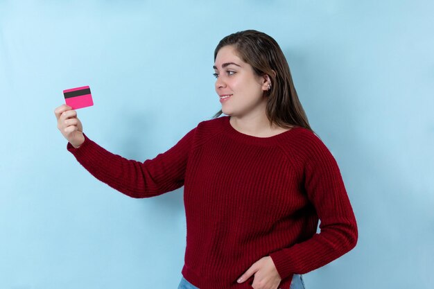 Junge frau, die eine kreditkarte lokalisiert über hellblauer wand hält