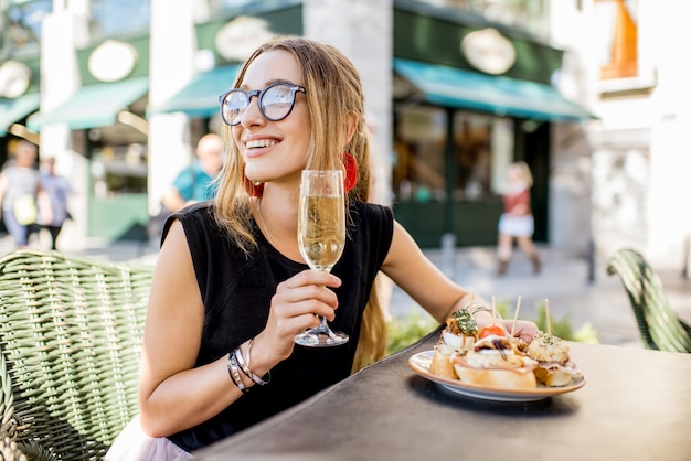 Junge Frau, die eine leckere Vorspeise mit Pinchos, traditionellem spanischen Snack und einem Glas Wein im Freien an der Bar in Valencia genießt?