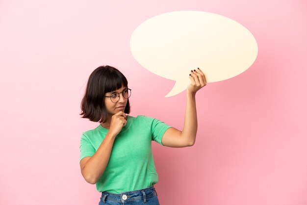 Junge Frau, die eine leere Sprechblase hält und denkt