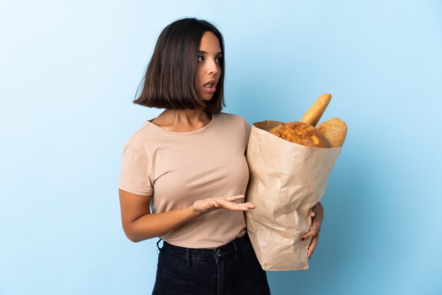 Junge Frau, die eine Papiertüte mit Brot hält