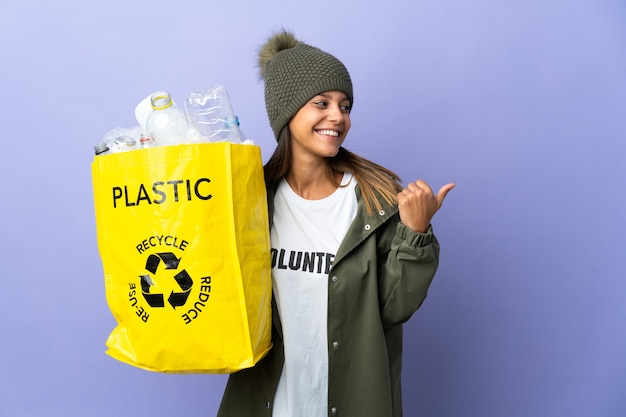 Junge Frau, die eine Tasche voll Plastik hält, die zur Seite zeigt, um ein Produkt zu präsentieren