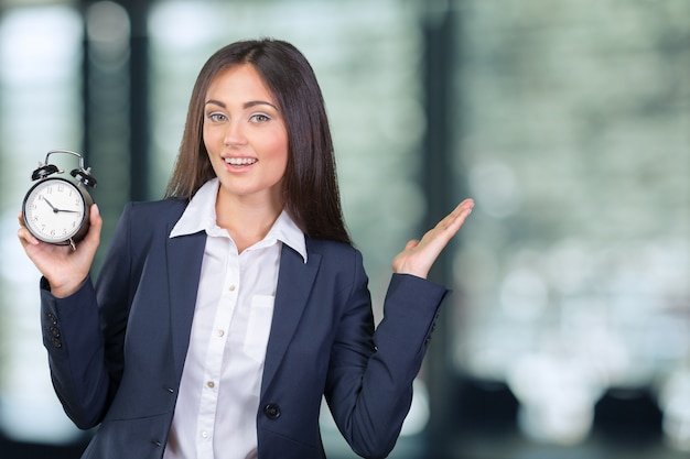 Junge Frau, die eine Uhr hält. Zeitmanagement-Konzept.