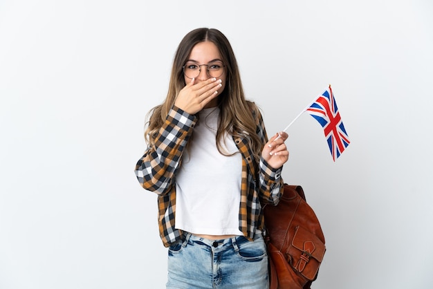 Junge Frau, die eine Vereinigte Königreichsflagge lokalisiert glücklich und lächelnd bedeckt Mund hält