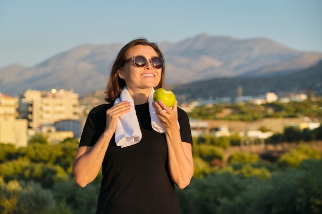 Junge Frau, die einen Apfel draußen isst