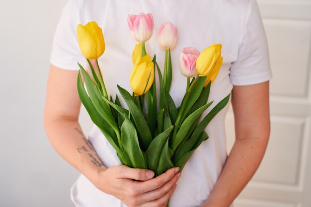 Junge Frau, die einen Blumenstrauß der festlichen Frühlingstulpen in ihren Händen hält