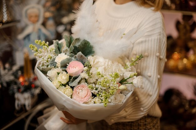 Junge Frau, die einen Blumenstrauß von Rosen, Hortensien und silbernen Orchideen hält