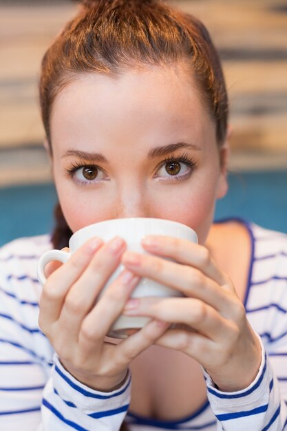 Junge Frau, die einen Cappuccino isst