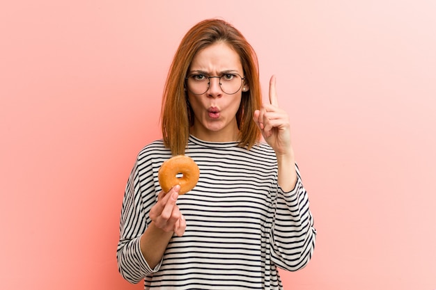 Junge Frau, die einen Donut hat irgendeine großartige Idee, Konzept der Kreativität hält.