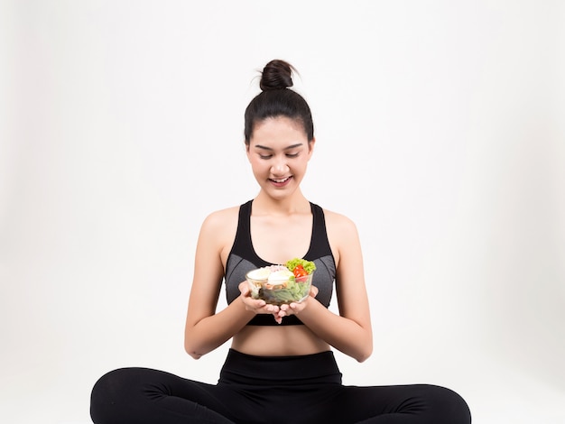 Junge Frau, die einen gesunden Obstsalat nach Training isst.