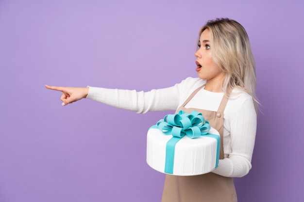 Junge Frau, die einen Kuchen über isolierter Wand hält