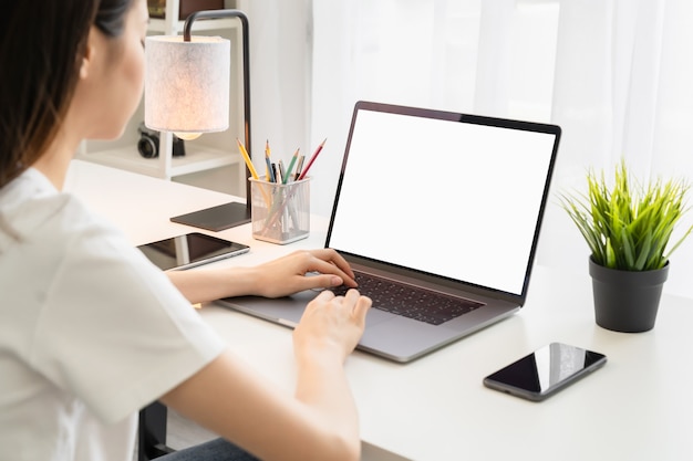 Junge Frau, die einen Laptop am Schreibtisch benutzt