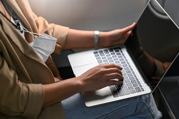 Junge Frau, die einen Laptop während des Reisens benutzt.