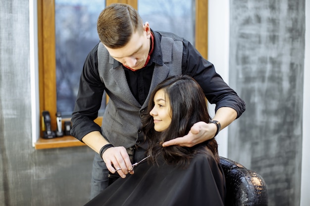 Junge Frau, die einen neuen Haarschnitt am Frisörsalon erhält.