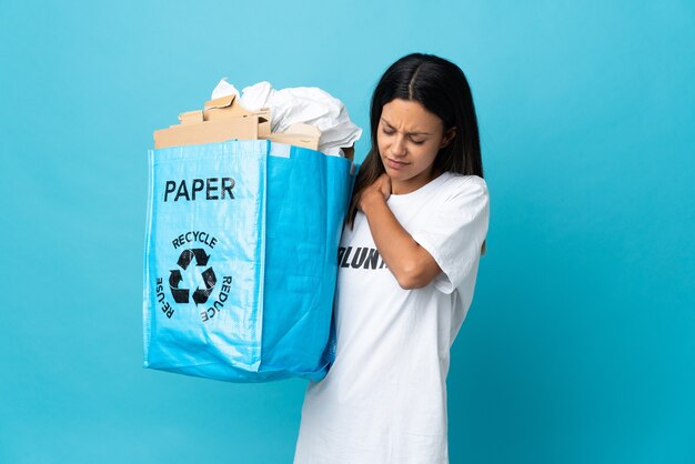 Junge Frau, die einen Recyclingbeutel voll Papier hält, der unter Schulterschmerzen leidet, weil sie sich bemüht hat